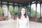 Beautiful curly hair girl in a light blue simple dress in a pavilion in a garden