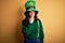 Beautiful curly hair woman wearing green hat with clover celebrating saint patricks day bored yawning tired covering mouth with