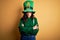 Beautiful curly hair woman wearing green hat with clover celebrating saint patricks day skeptic and nervous, disapproving