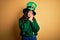 Beautiful curly hair woman wearing green hat with clover celebrating saint patricks day sleeping tired dreaming and posing with