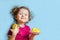 Beautiful curly happy girl with mango on blue background.