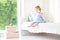 Beautiful curly toddler girl sitting on a white bed