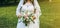 Beautiful curvy bride is holding wedding bouquet in hands. Overweight happy woman. Love story outdoors. White lace dress and veil