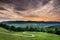 Beautiful curvy country road with fir trees in background during the sunrise colourful clouds