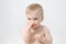 Beautiful cute adorable blonde caucasian naked baby girl on grey background, holding nose, feeling bad smell.Healthy kid