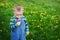 Beautiful cute boy in the park blowing on dandelion spring time