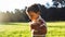 Beautiful cute boy in park blowing on dandelion in summer time at the sunset.