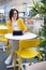 Beautiful cute brunette in a yellow jacket talking on the phone. Young businesswoman in a cafe using a digital tablet