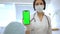 beautiful cute doctor in medical mask in medical office holds smartphone with chroma key in her hand. general