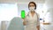 Beautiful cute doctor in medical mask in medical office holds smartphone with chroma key in her hand. General