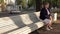 Beautiful cute elderly woman sitting on a park bench blue