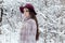 Beautiful cute elegant girl in a fur coat and hat walking in the winter forest bright frosty morning