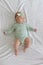 beautiful cute european baby girl with a bow on her head and a green bodysuit lies on her back on a white background