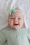 beautiful cute european baby girl with a bow on her head lies on her back on a white background