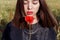 Beautiful cute girl with big lips and red lipstick in a black jacket with a flower poppy standing in a poppy field at sunset