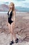 Beautiful cute girl in a fashion shoot in a bathing suit in desert dry cracked earth in the background of the mountains