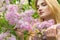 Beautiful cute girl in lilac flowering trees in the summer warm day