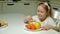 A beautiful cute girl refuses a plate of snacks, chocolate, chips, takes a plate of fruits. A portrait