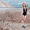 Beautiful cute girl in swimsuit fashion shoot in desert with dry cracked ground background mountains under