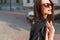 Beautiful cute happy smiling brunette girl in the big sunglasses walking around the city at sunset