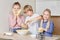 Beautiful cute kids blond siblings helping mom in the kitchen.