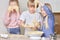 Beautiful cute kids blond siblings helping mom in the kitchen.