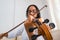 Beautiful and cute latina woman playing violin at home