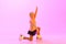 Beautiful, cute little girl, child, training figure skating against pink background in neon light. Kid in sweater and
