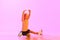Beautiful, cute little girl, child, training figure skating against pink background in neon light. Kid in sweater and