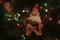 Beautiful cute toy Santa Claus with gifts on the Christmas tree with colorful garlands. Festive decorations. Toy Santa Claus