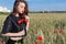 Beautiful cute young woman with full lips with short hair in a field with poppy flowers in their hands
