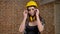 Beautiful cute young women in helmet and headphones looking straight into camera and putting on glasses, female builder