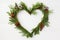 Beautiful cypress Christmas wreath from green twigs red berries in the shape of a heart with ornament on white wood background.