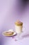 Beautiful dalgona drink a frothy coffee in a transparent mug and flowers of lilac on a purple background. Sweets on a plate: Donat