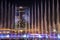 Beautiful dancing fountain illuminated at night against the backdrop of the Hilton hotel in new Tashkent City Park.
