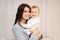 a beautiful dark-haired woman holds a one-year-old boy in her arms.