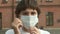 Beautiful dark haired young girl putting protective medical face mask on being on the street