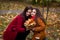 Beautiful daughter teenager gently hugs mom with closed eyes. A girl in an orange jacket with luxurious hair. Woman in red with a