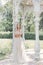 Beautiful delicate bride girl in a light beige wedding dress walks in the garden bright sunny warm day