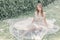 Beautiful delicate bride girl in a light beige wedding dress walks in the garden bright sunny warm day