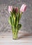 Beautiful delicate pink tulips in a glassy glass against a light background