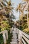 A beautiful descent wooden staircase through the jungle down to the beach. A beautiful view opens through palm trees to the ocean