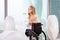 Beautiful disabled bride posing in a wheelchair against the background of a panoramic window overlooking the skyscrapers