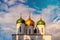 Beautiful domes with golden crosses over the fortress walls in Russia against the blue clear sky