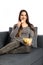 Beautiful domestic girl eating chips, watching tv, sitting at sofa on white