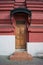 A beautiful door made of natural wood is varnished under an openwork black wrought iron porch on an old red brick building