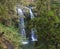 Beautiful double waterfall at Salto da Farinha falling from rocks in lush green rainforest vegetation, Sao Miguel