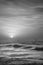 Beautiful dramatic black and white stormy landscape image of waves crashing onto beach at sunrise