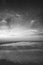 Beautiful dramatic black and white stormy landscape image of waves crashing onto beach at sunrise