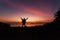 Beautiful dramatic sunrise with man standing raised-up arms enjoying freedom on the mountain.